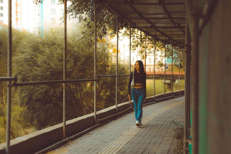 Une jeune femme marche dans une allée urbaine bordée de verdure