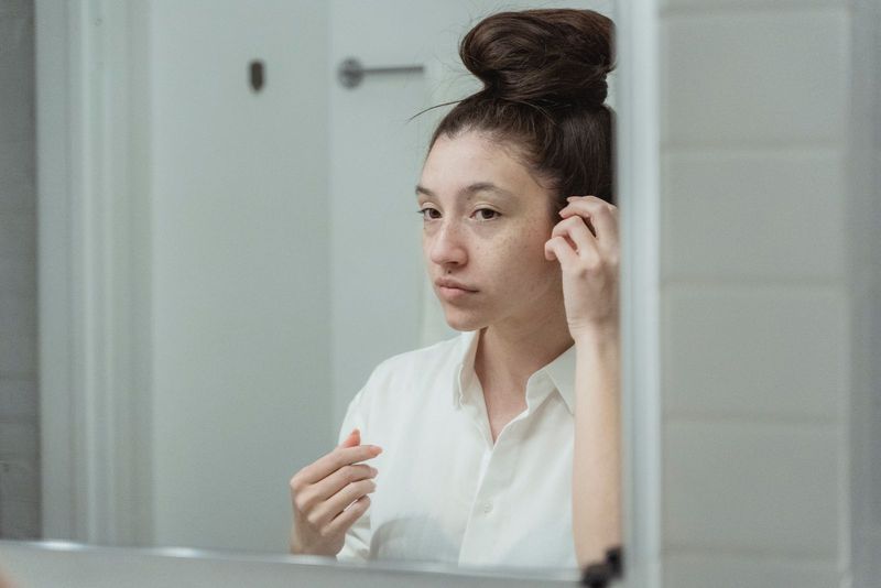 Une jeune femme se recoiffe devant son miroir, le matin