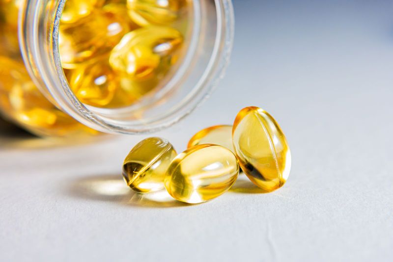 Gélules ambrées d’ubiquinol renversées hors de leur flacon