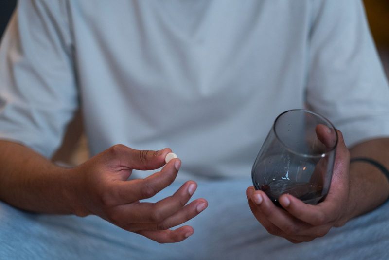Un homme tient une gélule et un verre d’eau