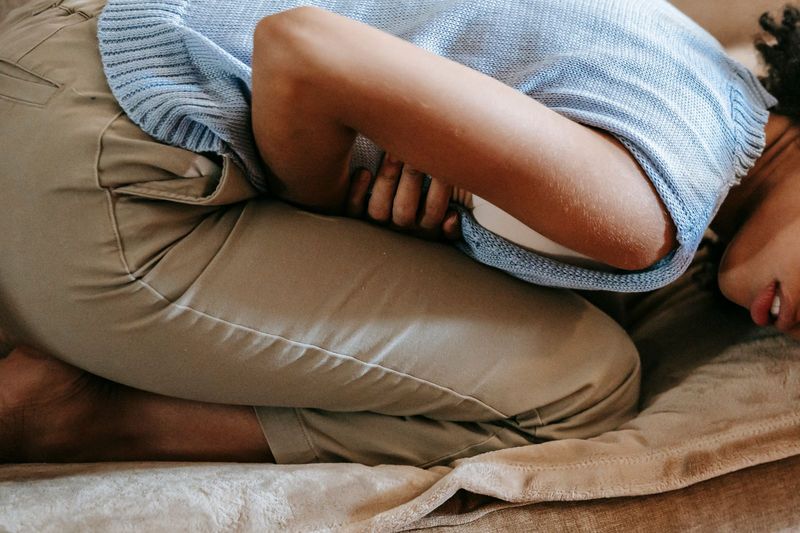 Une personne allongée sur un canapé, une main sur le ventre