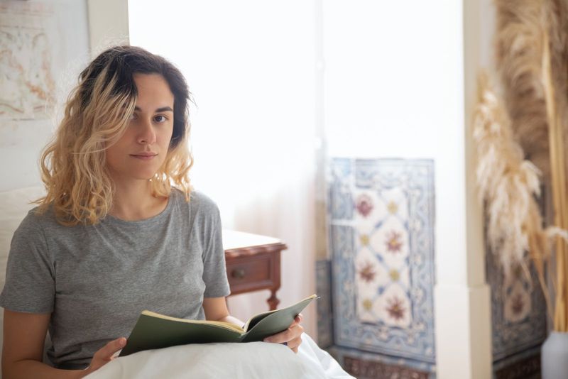 Une jeune femme lit un livre dans une chambre lumineuse
