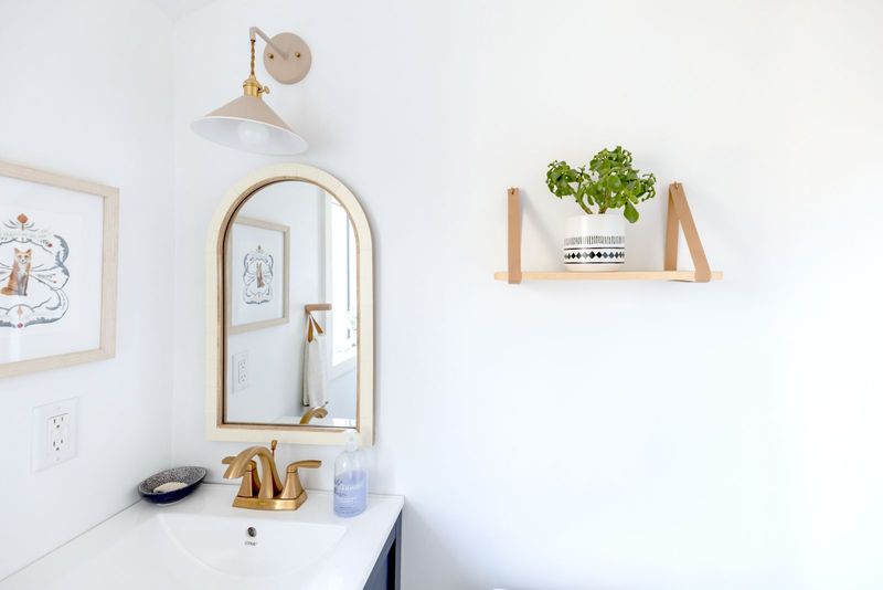 Une salle de bain claire, étagère de bois et miroir