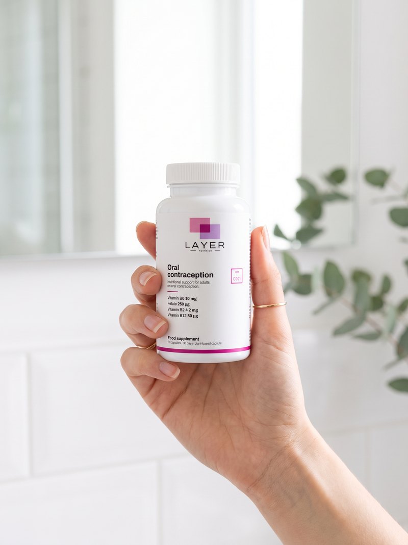 A hand holds the Layer Nutrition Contraception bottle