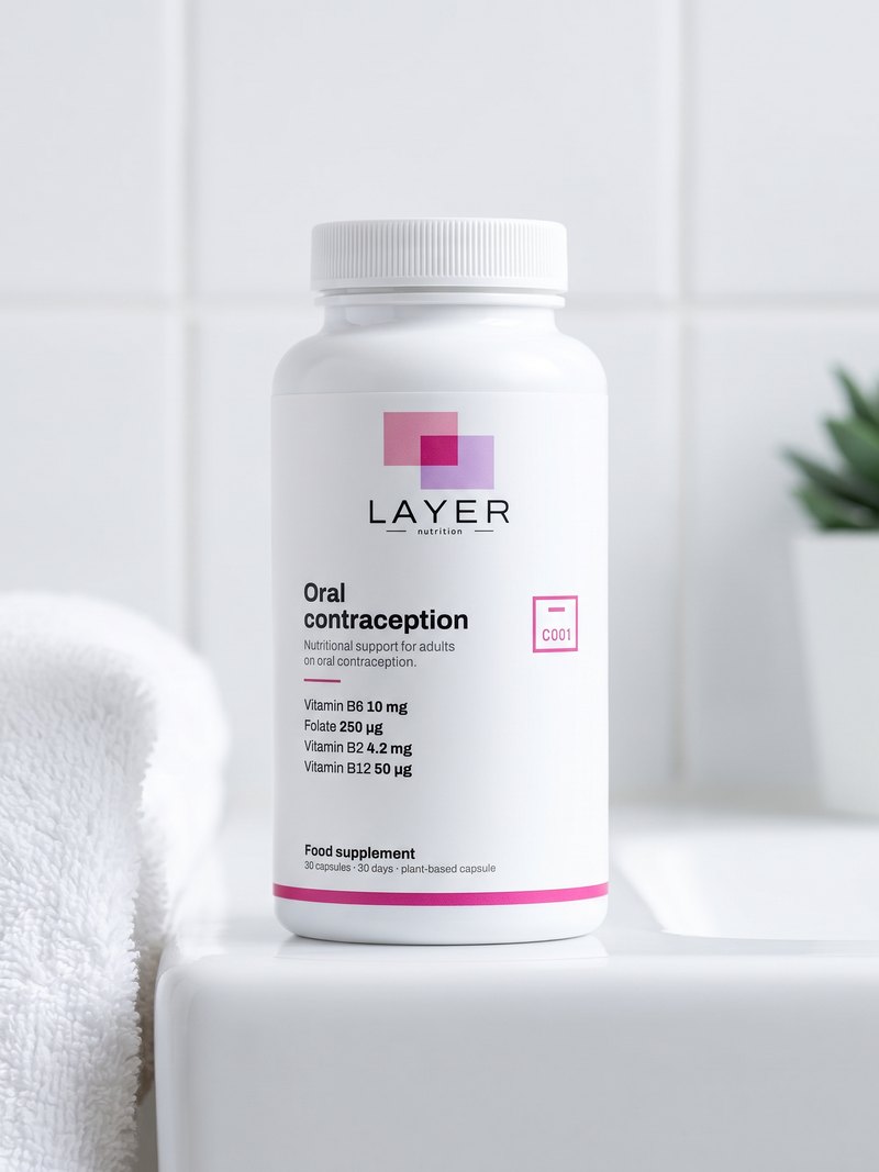 A hand holds the Layer Nutrition Contraception bottle in a bright bathroom