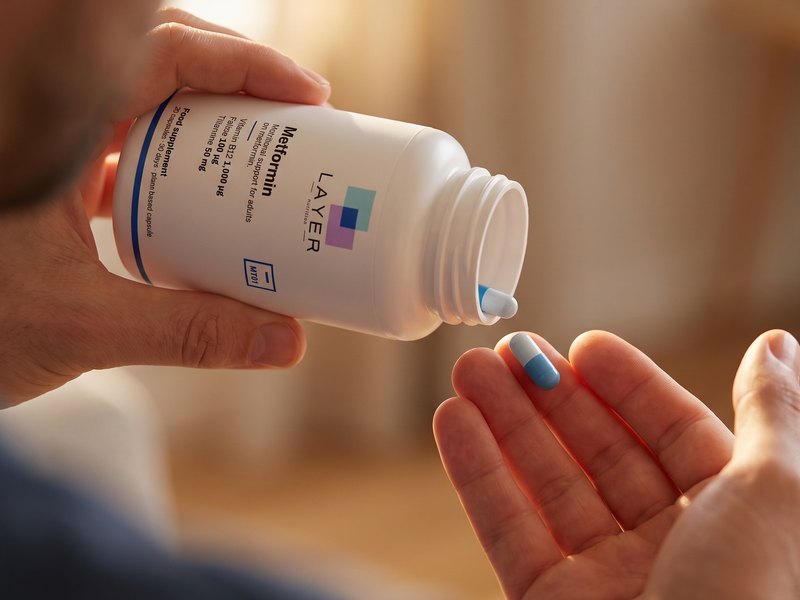A capsule poured into the hand from the Layer Nutrition Metformin bottle