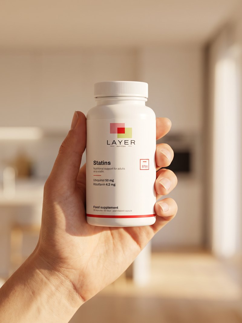 A hand holds the Layer Nutrition Statins bottle, in a bright interior