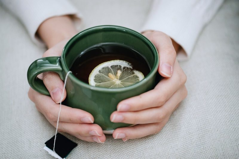 Hands holding a cup of lemon herbal tea